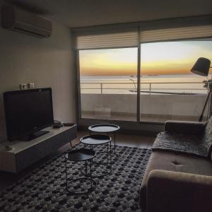 - un salon avec un canapé et une grande fenêtre dans l'établissement Dos Orillas - Apartamento 510, à Colonia del Sacramento