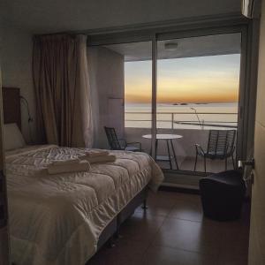 a bedroom with a bed and a balcony with a table at Dos Orillas - Apartamento 510 in Colonia del Sacramento