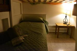 a bedroom with a bed and a table with a lamp at Altos de Santiago Bed & Breakfast in San Miguel de Tucumán