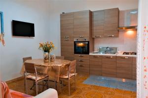 una cucina con tavolo, sedie e televisore di Villa Sette Nani a Torre Lapillo