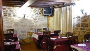 a dining room with tables and chairs and a tv at Hotel Rural Villa de Silos in Santo Domingo de Silos