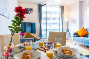 a table with plates of food and a vase with a rose at Inners City Apartments -On Suites in Birmingham