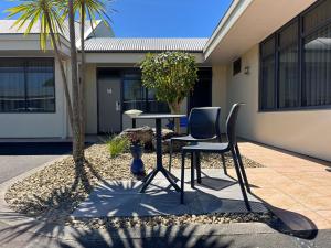 a table and two chairs in front of a house at Academy Motor Inn in Tauranga