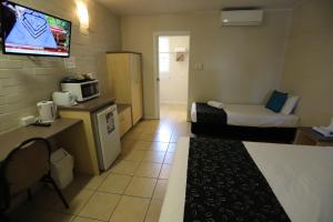 a small hotel room with a bed and a tv at Tropic Coast Motel in Mackay