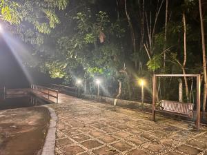 un parc de nuit avec un banc et des lumières dans l'établissement CASA DUPLEX em CONDOMÍNIO à beira do RIO PREGUIÇAS, à Barreirinhas