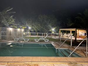 uma piscina à noite com duas cadeiras em CASA DUPLEX em CONDOMÍNIO à beira do RIO PREGUIÇAS em Barreirinhas