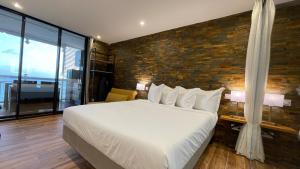 una camera da letto con un letto grande e un muro di mattoni di Vue Mer & Rocher - Okavango Blue Studio a Le Diamant Altre 14 foto