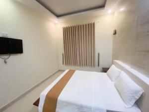 biała sypialnia z łóżkiem i telewizorem w obiekcie Thien Phu Nghia 2 - Hotel Phu Quoc w Duong Dong