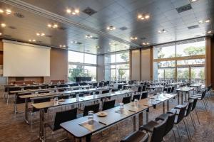 a large room with tables and chairs and a projection screen at PCM Forum Alcalá in Alcalá de Henares +37 photos