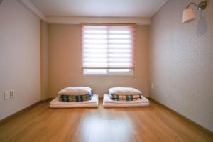 two beds in a room with a window at Lighthouse Guesthouse in Mokpo