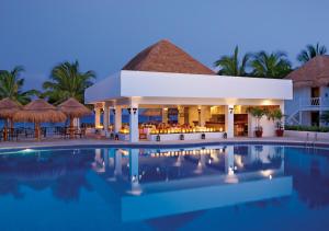 un complexe avec une piscine ouverte la nuit dans l'établissement Sunscape Sabor Cozumel, à Cozumel