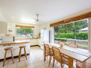 a kitchen with a table and chairs and a large window at Gardina Place in Iluka
