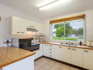 a kitchen with white cabinets and a large window at Gardina Place in Iluka