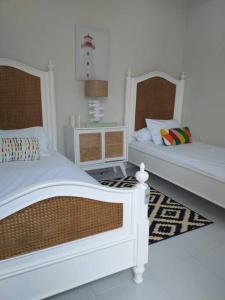 two beds in a room with white walls at Maison de Q - 2 BR at Villa Ubud B 12 Anyer in Babagan