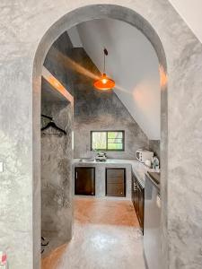 an archway in a kitchen with a stone wall at Baan Rai Me Rak Organic Farmstay in Ban Pa Khlok