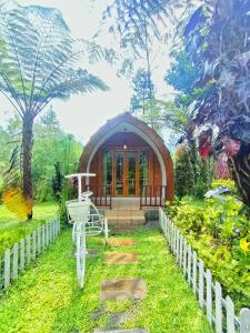 a small house in the middle of a garden at Pagupon Camp Syariah in Batu