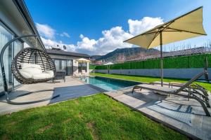 un patio con una silla y una sombrilla junto a la piscina en 2 Bedroom Private Villa en Kayakoy