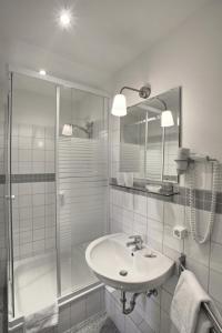 a white bathroom with a sink and a shower at Hotel Abendstern in Berlin