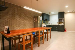 una cucina con un lungo tavolo in legno e sedie di Lighthouse Guesthouse a Mokpo