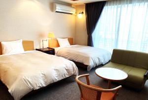 Cette chambre comprend deux lits, un canapé et une table. dans l'établissement Hotel Kosaka Gold Palace, à Kosaka