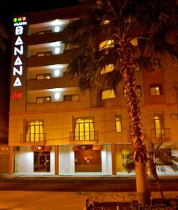 a palm tree in front of a building at night at Hotel Puerto Banana in El Guabo