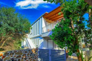 a white house with a blue fence and trees at Bitsakis Family II - Paleochora Luxury House in Palaiochora