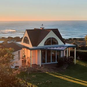 a house with the ocean in the background at The Quarters Ocean-View Chalet in Gisborne