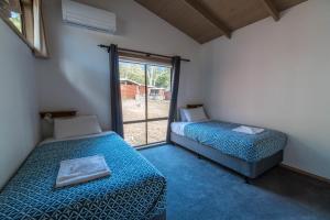 two beds in a room with a window at Wonderland Cottages in Halls Gap