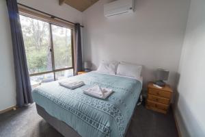 a bedroom with a bed and a large window at Wonderland Cottages in Halls Gap