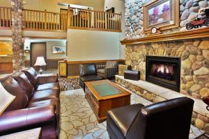 a living room with leather furniture and a fireplace at AmericInn by Wyndham Lincoln North in Lincoln