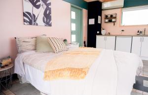 a bedroom with a white bed and a kitchen at The Quarters Ocean-View Chalet in Gisborne