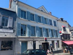 a building with blue shuttered windows and a car on a street at La Loge des Artistes in Honfleur