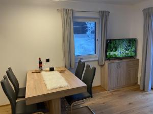 a dining room with a table and a television at Seereith Apartments in Brixen im Thale