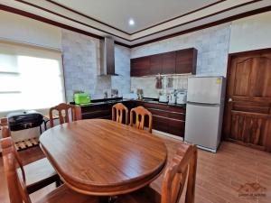 cocina con mesa de madera y nevera en Sand-D House Pool Villa A15 at Rock Garden Beach Resort Rayong en Mae Pim