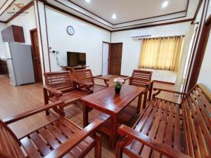 Habitación con sillas de madera, mesa y TV. en Sand-D House Pool Villa A15 at Rock Garden Beach Resort Rayong en Mae Pim