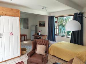 a bedroom with a bed and a chair at Santika Garden Cottage Stellenbosch in Stellenbosch