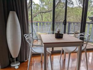 a table and chairs in a room with a balcony at Romantic Cabin Escapes Barrington Tops - Lorikeet in Bandon Grove