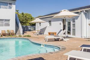 a swimming pool with a patio and a house at Southeaster in Bloubergstrand
