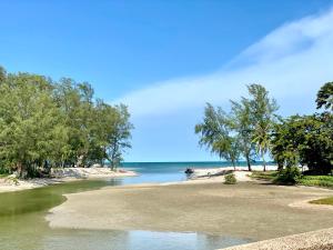 una playa con árboles y el océano en un día soleado en Sand-D House Pool Villa C18 at Rock Garden Beach Resort Rayong, en Mae Pim