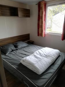 uma cama não feita num quarto com uma janela em Location Mobil Home em Vias