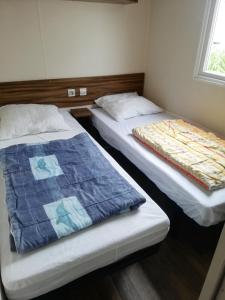 Dos camas en una habitación pequeña con 3 estrellas que dice que es lo que dice en Location Mobil Home en Vias