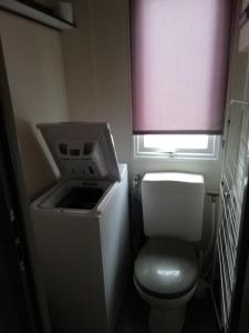 a small bathroom with a toilet and a window at Location Mobil Home in Vias