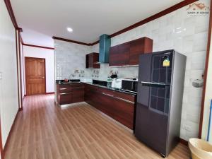 een keuken met een zwarte koelkast en houten kasten bij Sand-D House Pool Villa A8 at Rock Garden Beach Resort Rayong in Ban Ao Makham Pom
