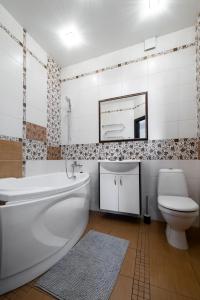 a bathroom with a tub and a toilet and a mirror at Apartamentai prie Meriadiano in Klaipėda