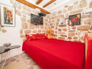 a teddy bear sitting on a red bed in a room at Apartment Alexandra in Kotor