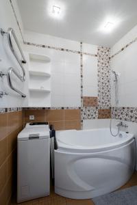 La salle de bains est pourvue d'une baignoire blanche et de toilettes. dans l'établissement Apartamentai prie Meriadiano, à Klaipėda
