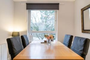 uma mesa de jantar com cadeiras e um vaso de flores em Two Bedroom Ground Floor Flat em Bridge of Allan