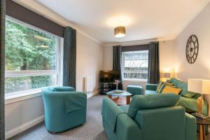 a living room with chairs and a couch and a tv at Two Bedroom Ground Floor Flat in Bridge of Allan