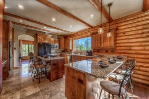 una cocina con armarios de madera y una gran isla con taburetes. en Big Sky, 6 BRs, Loft, Decks, Gameroom, Sleeps 16, en Ruidoso