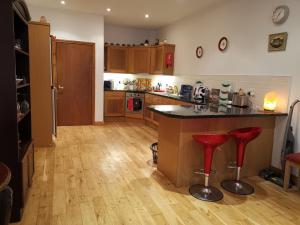 a kitchen with a counter and red stools at Ground Floor Slievemore Apartment in Bellanasally